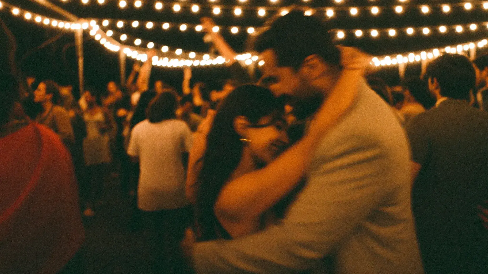 A couple dancing bachata on a crowded social floor at night